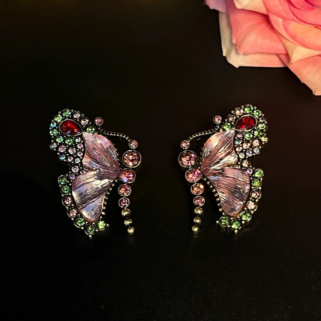 Butterfly-shaped earrings with gemstones on a dark background