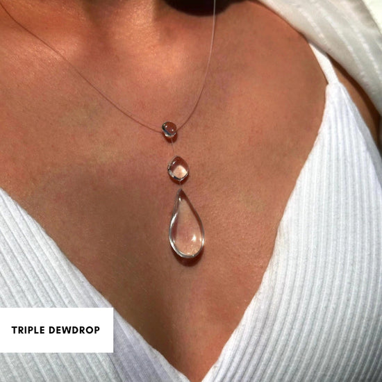 Triple dewdrop transparent necklace on a person wearing a white top