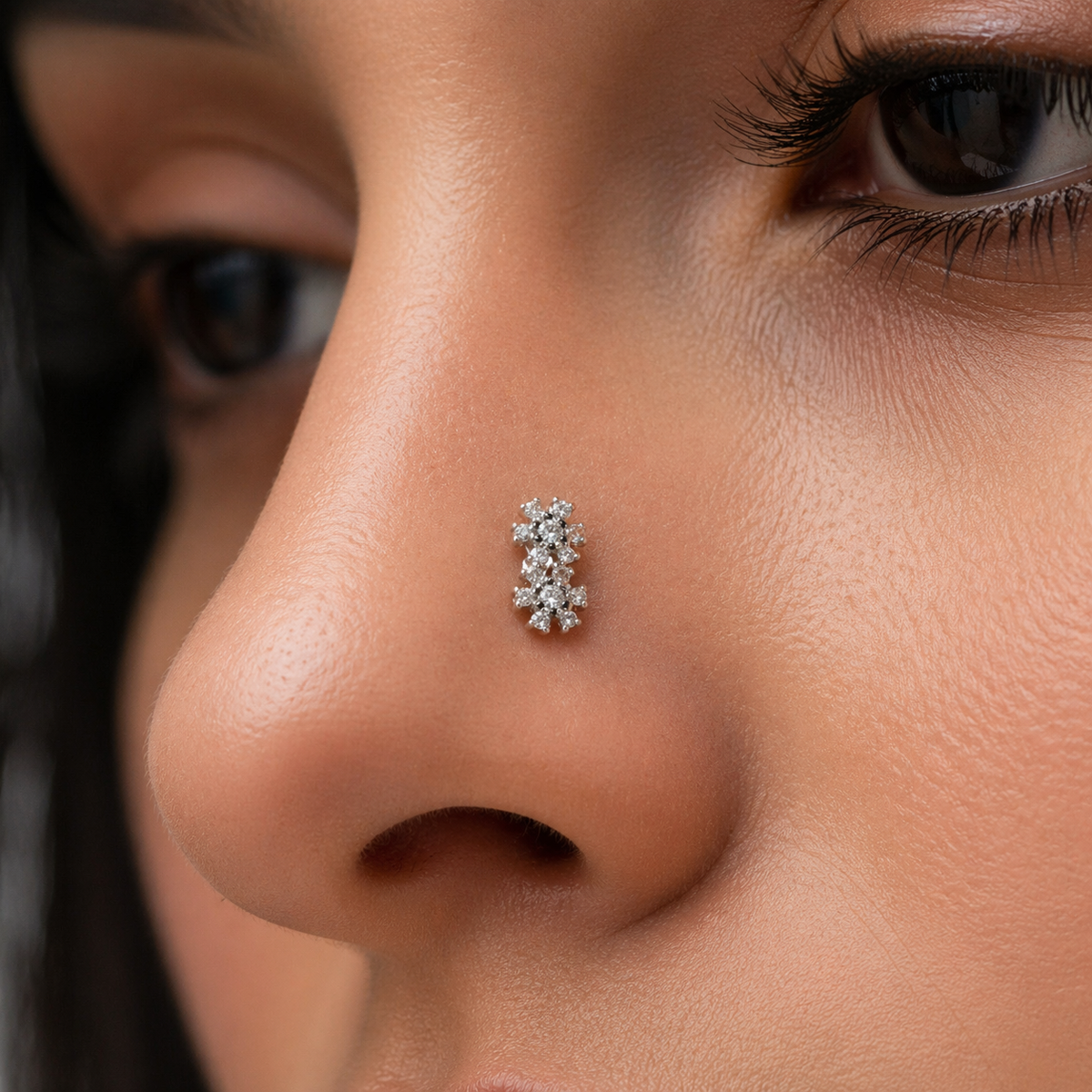 Close-up of a person wearing a silver snowflakes nose ring with a diamond-like stone.