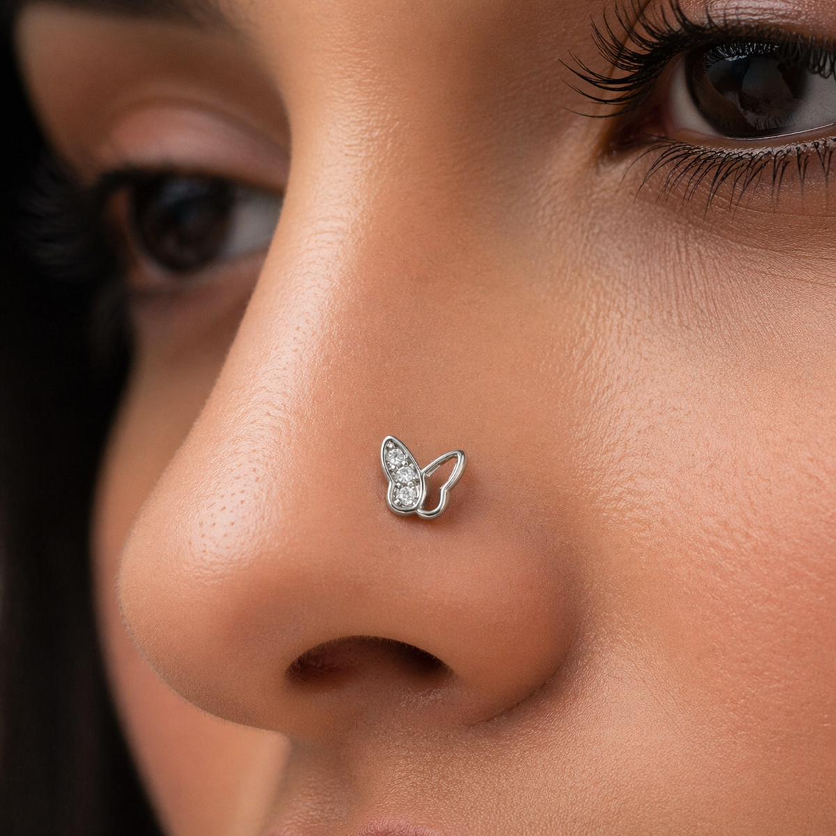 Close-up of a person wearing a butterfly-shaped nose ring.