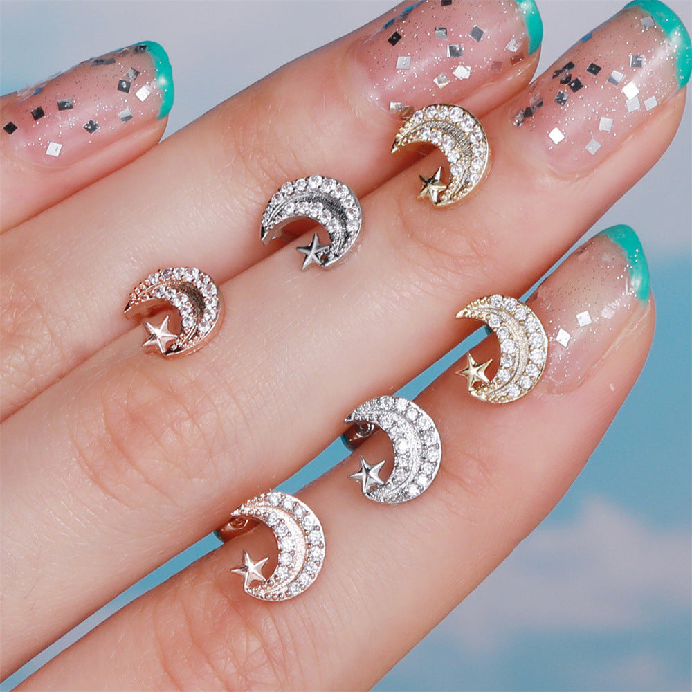 Rose gold, white gold, and gold cubic zirconia moon and star cartilage studs displayed on a hand with glittery nail art