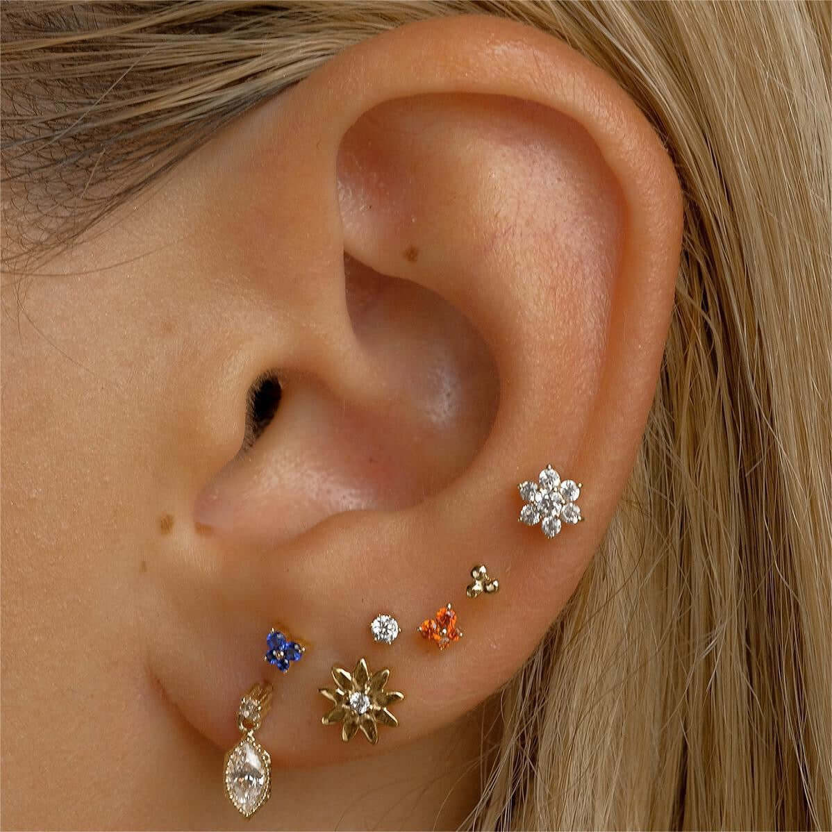 14K gold floral birthstone cartilage, helix, and daith earrings adorned on ear, showcasing various colorful birthstones for each month.