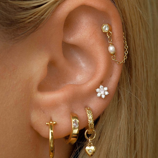 Woman wearing 14K gold floral birthstone cartilage earrings, displaying helix and daith piercings with elegant gold jewelry.