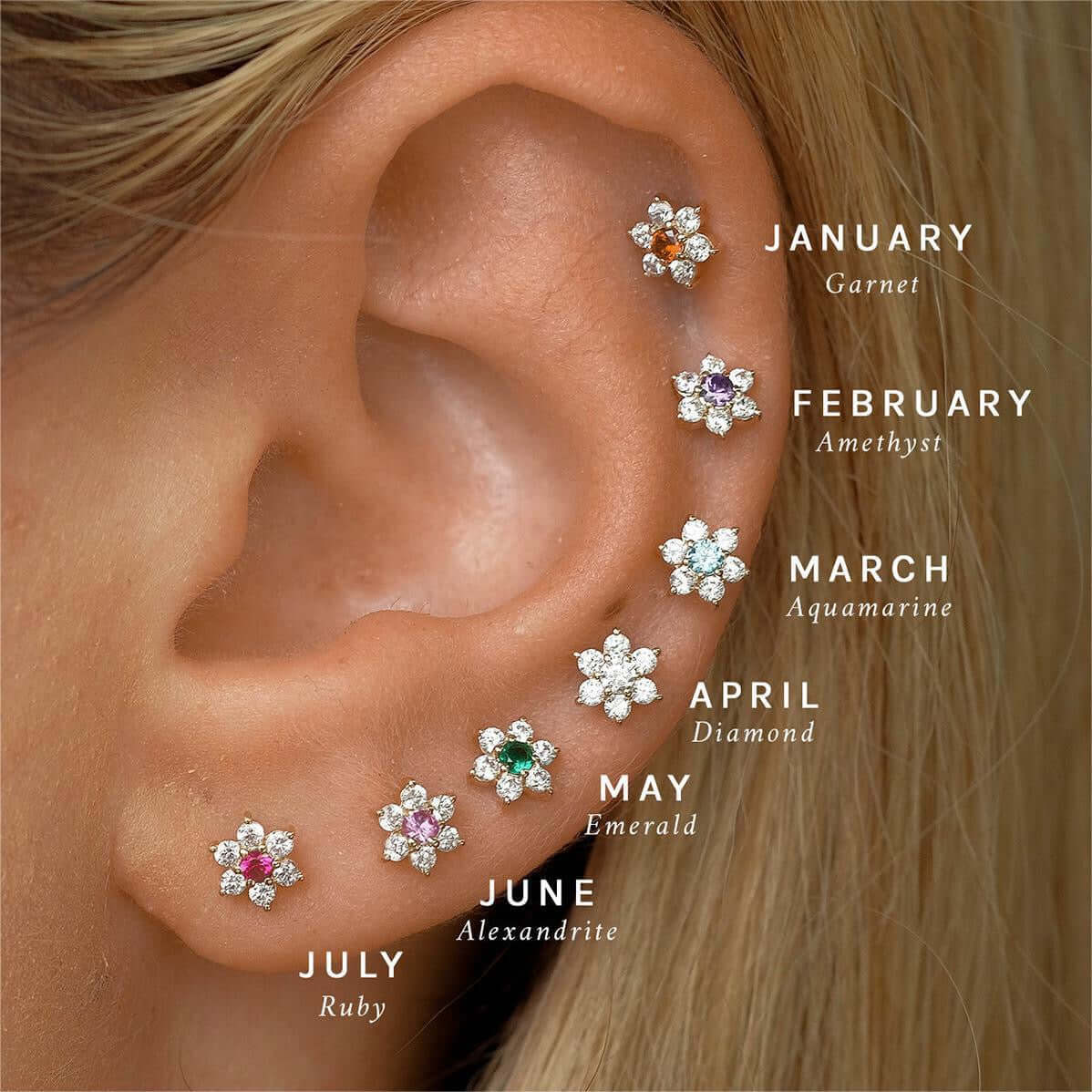 14K gold floral birthstone cartilage earrings for each month shown on ear, including garnet, amethyst, aquamarine, diamond, emerald, alexandrite, and ruby