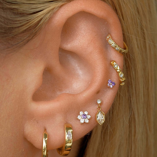 Close-up of ear with 14K gold floral birthstone cartilage earrings, including helix and daith earrings for a stylish and elegant look.