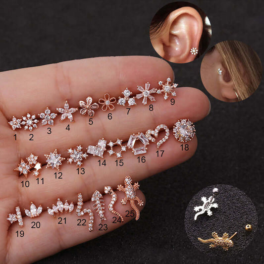 Assorted 20G cartilage stud earrings in various designs including stars, flowers, and lizards displayed on a hand with ear piercings in the background