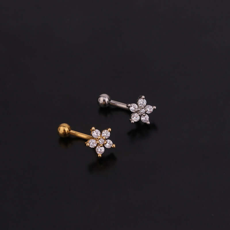 Gold and silver daith cartilage earrings with floral CZ design on a black background