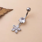 Silver belly button ring with floral design and clear gemstone on a beige background