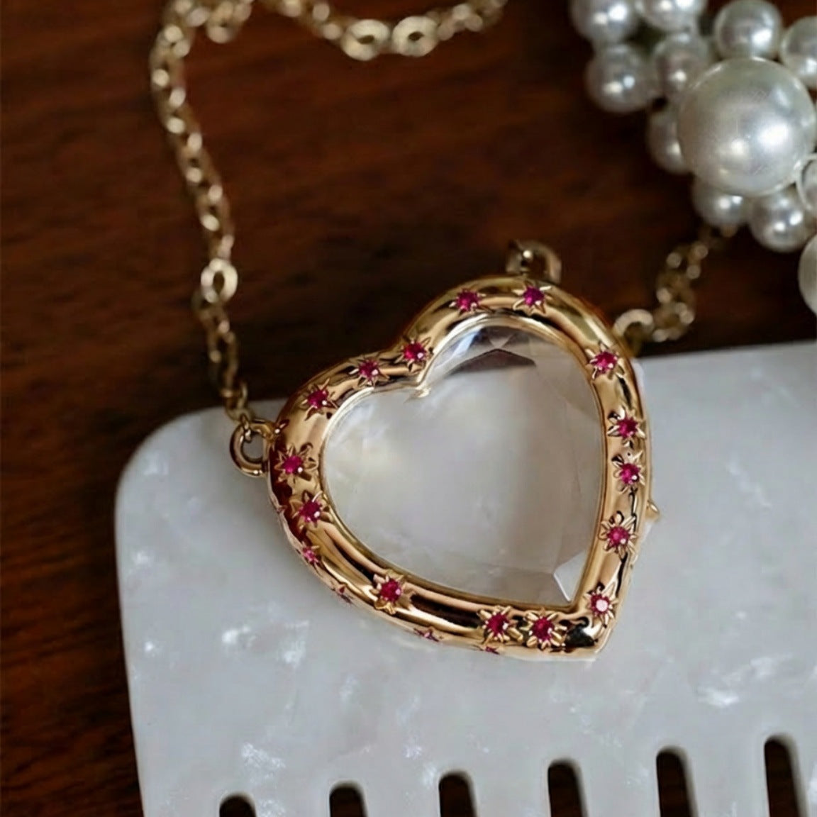 Gold heart-shaped necklace with pink stones on a white surface