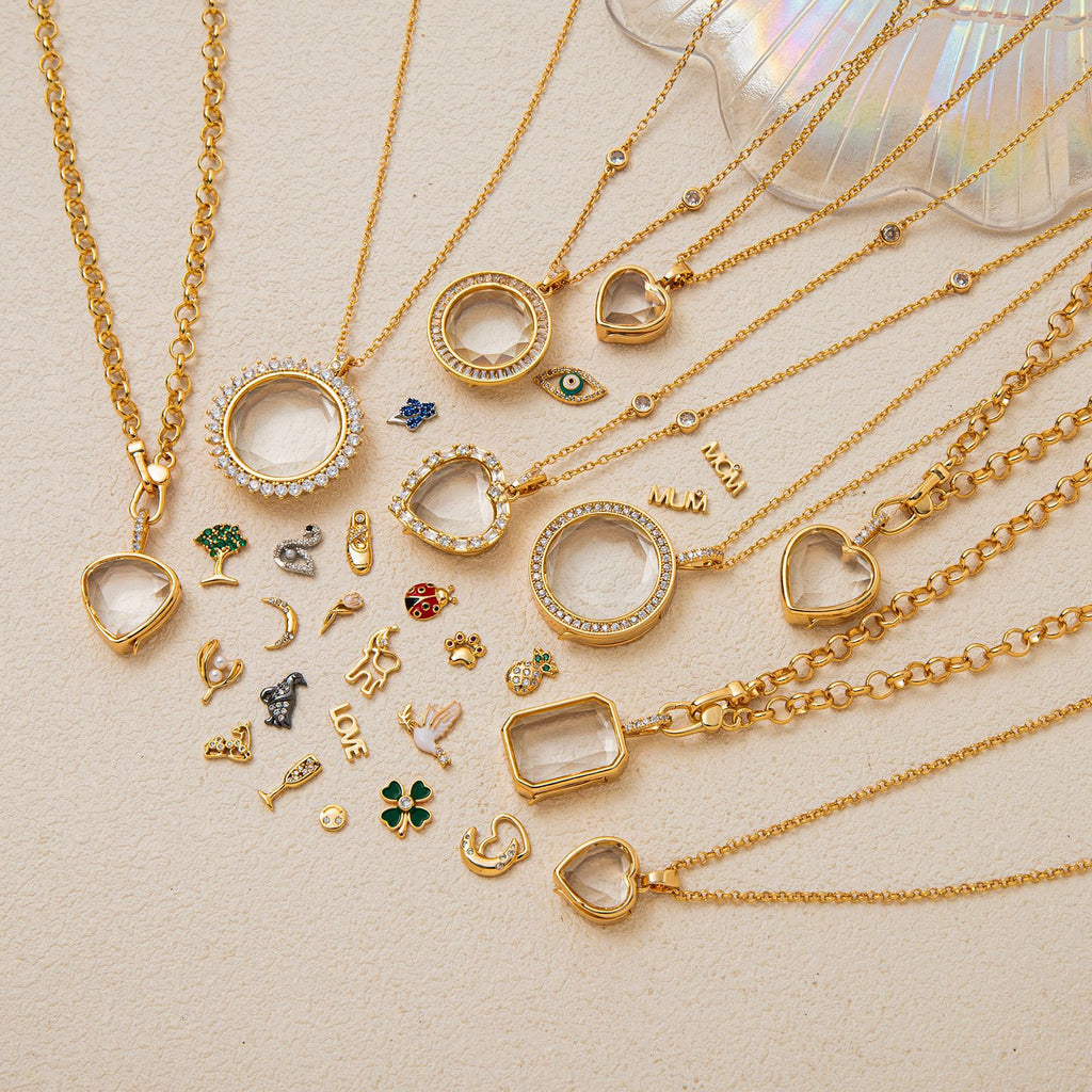 Gold necklaces with various pendants on a beige surface