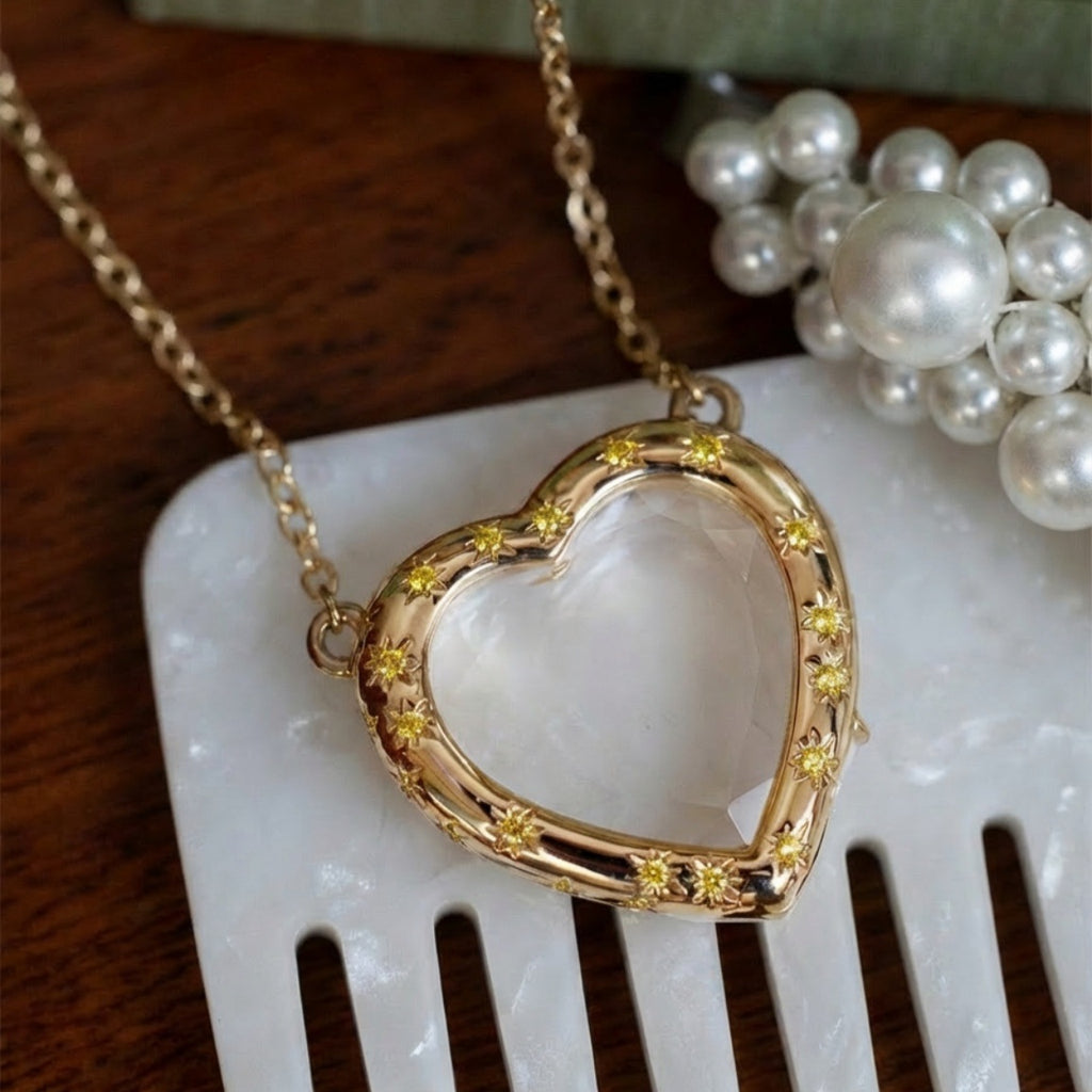 Gold heart-shaped necklace with embedded stones on a white surface