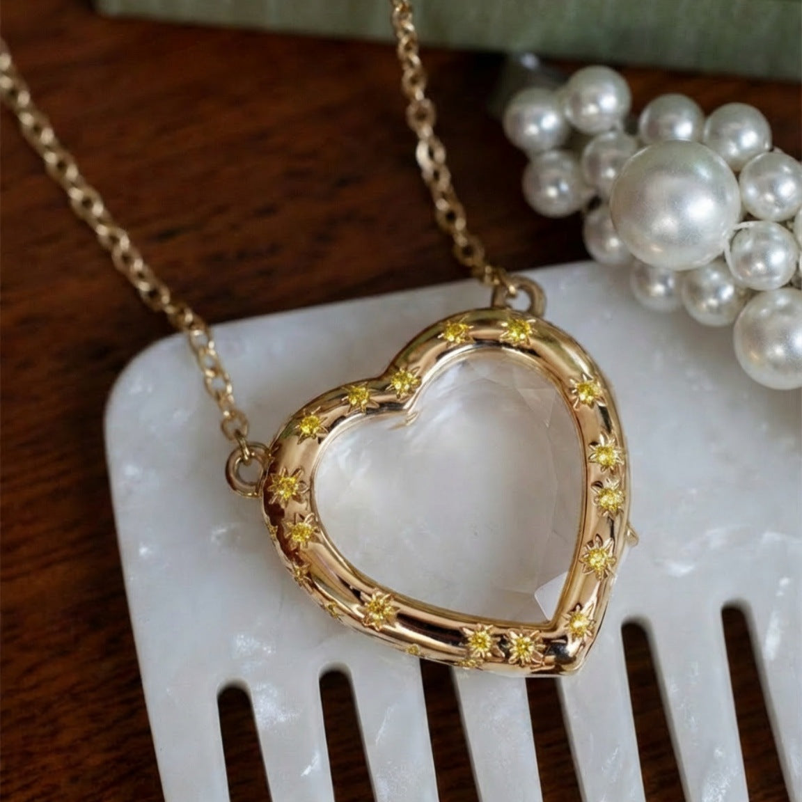 Gold heart-shaped necklace with embedded stones on a white surface
