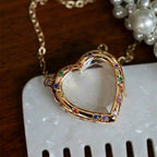Heart-shaped locket with colorful stones on a white surface