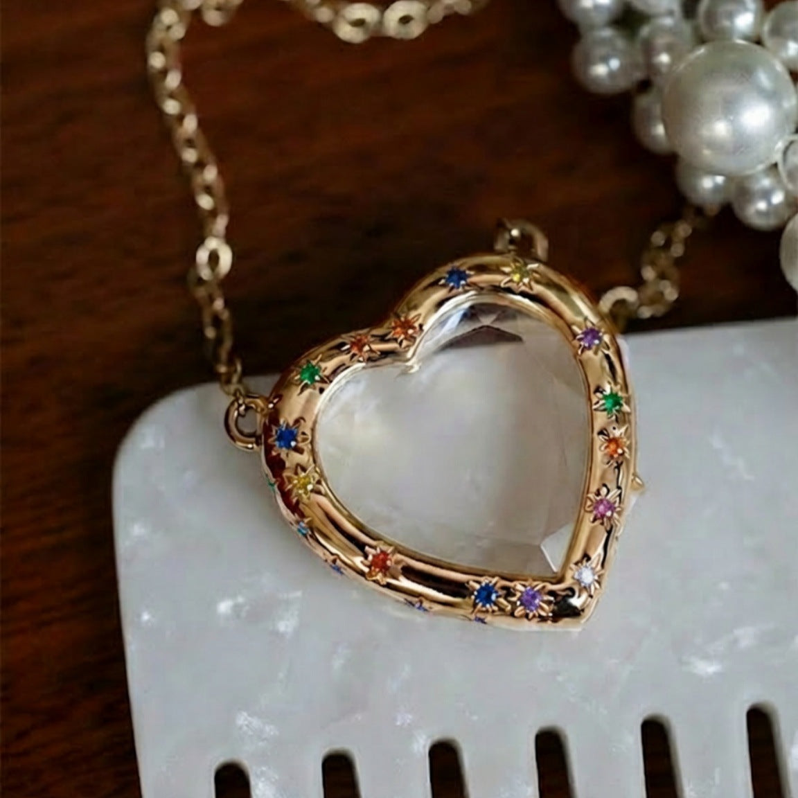 Heart-shaped locket with colorful stones on a white surface