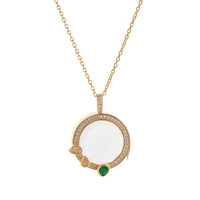 Gold necklace with a pendant featuring a white stone and green gem on a white background