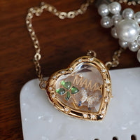 Heart-shaped gold locket with 'MAMA' and decorative elements on a white surface.