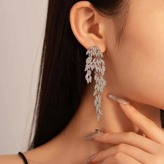Close-up of a person wearing a sparkling leaf-shaped earring.