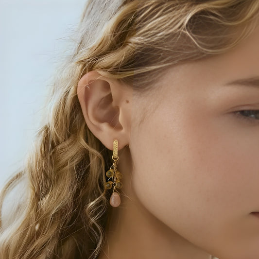 Close-up of a person wearing a sunstone drop earrings